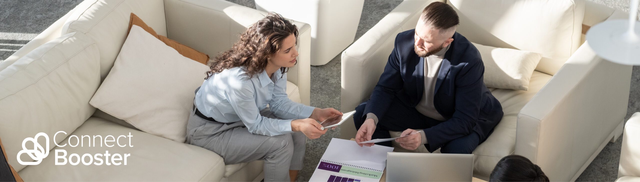 three professionals seated around a coffee table reviewing financials and a laptop